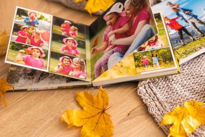 Colorful photo book on a wooden table with autumn leaves, showcasing seasonal printing in Calgary.